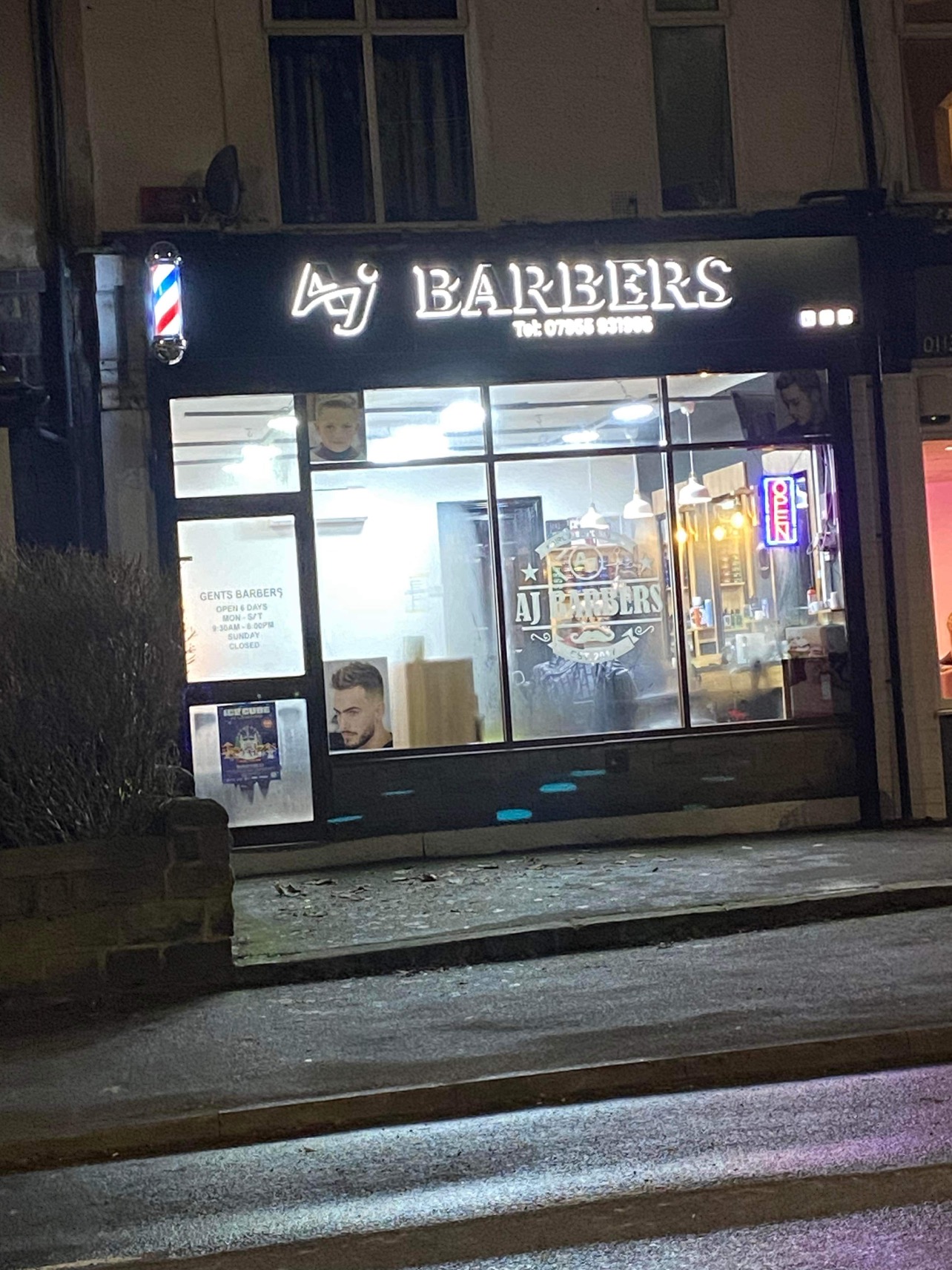 AJ Barbers lit up at night on Low Lane